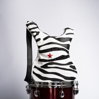 Rock Stripes este o geantă în stil rock, modelată în formă de chitară și realizată manual din piele eco italiană de înaltă calitate. Cu dungi zebra îndrăznețe și o stea roșie accent, acest accesoriu unic este perfect pentru concerte, festivaluri și ținute de zi cu zi care cer atenție.